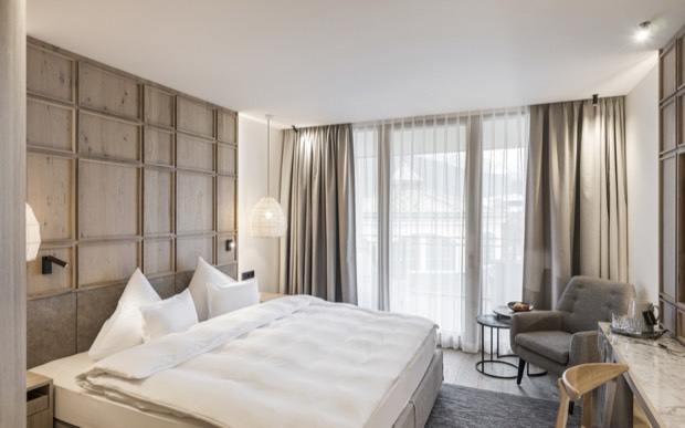Ein Doppelzimmer im Alpenresort Schwarz mit großem Bett und Fenstern zu den Bergen.