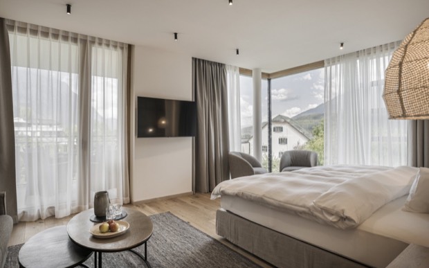 Ein Zimmer im Alpenresort Schwarz mit Doppelbett und Fenstern zum Bergpanorama.